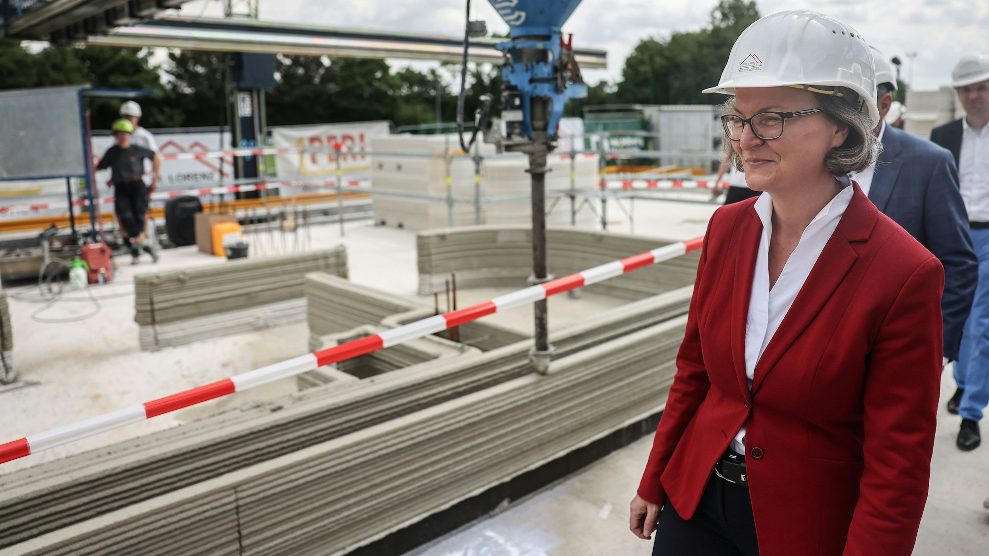 27.06.2023, Nordrhein-Westfalen, Nordkirchen: Ina Scharrenbach, (CDU), Ministerin für Heimat, Kommunales, Bau und Digitalisierung in Nordrhein-Westfalen, geht über die Baustelle von Europas erstem öffentlichen Gebäudes aus dem 3D-Drucker. Im Rahmen des Projekts «Digitalisierung der Bauwirtschaft und innovatives Bauen» wird das Vereinsheim des Sport-ClubCapelle digital gebaut. Der Druckbeton ist CO2-arm und voll recyclebar. Foto: Oliver Berg/dpa +++ dpa-Bildfunk +++