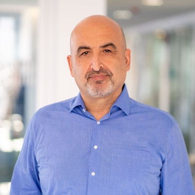 Auf dem Bild ist Tuncay Özdamar. Er trägt ein blaues Hemd.