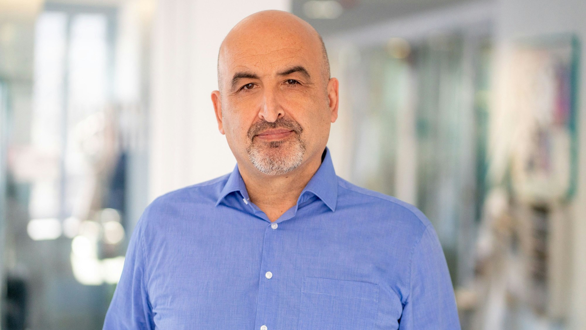 Auf dem Bild ist Tuncay Özdamar. Er trägt ein blaues Hemd.