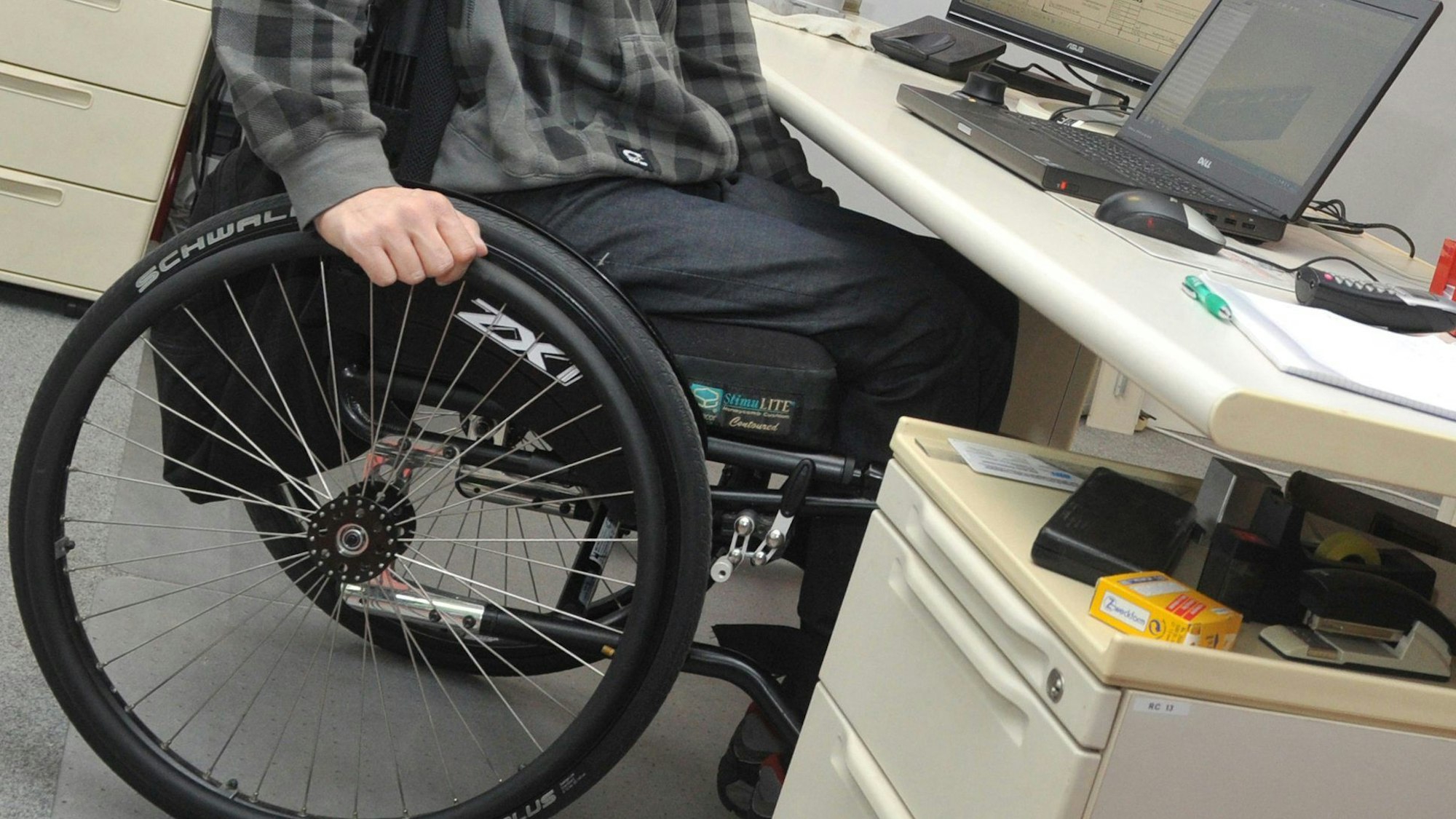 Ein Rollstuhlfahrer arbeitet an einem Schreibtisch.