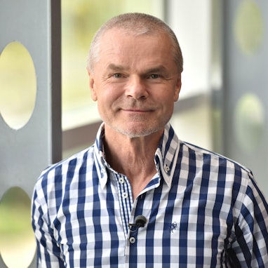 Jürgen Domian trägt ein weiß-blau-kariertes Hemd und blickt in die Kamera.