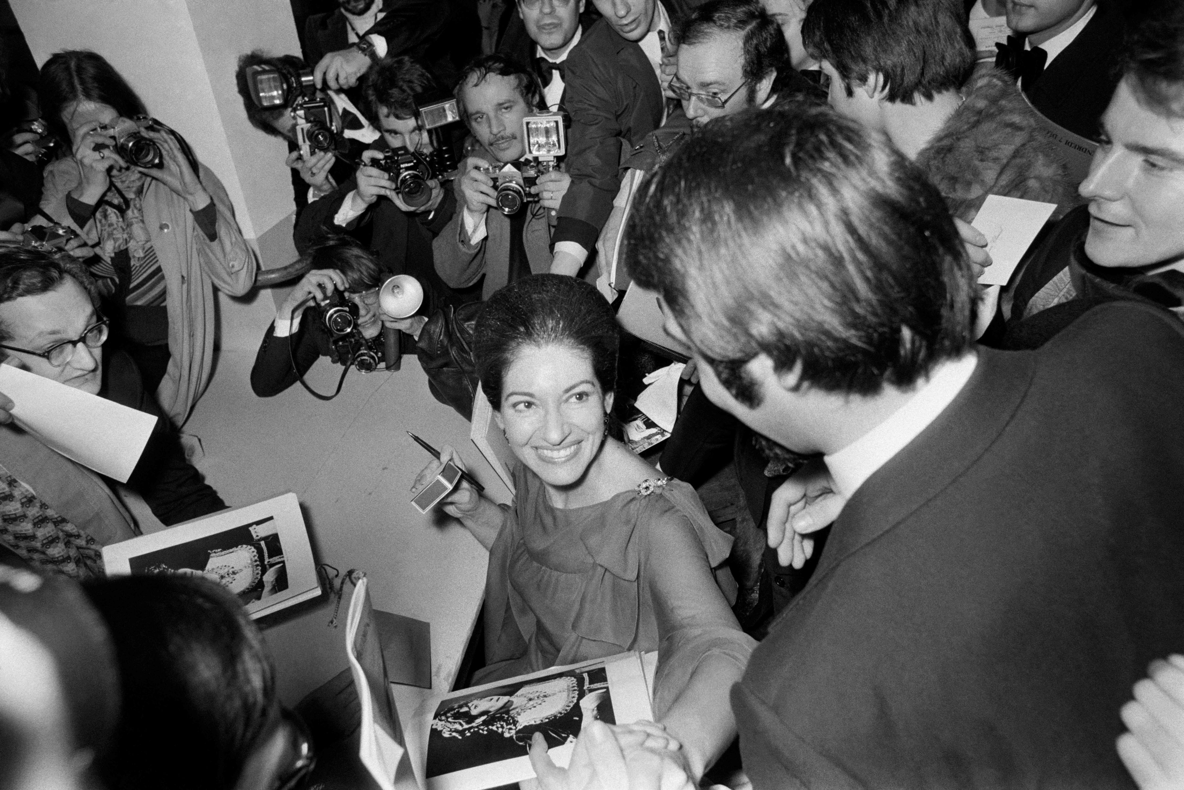 Maria Callas ist umgeben von Fotografen und gibt ihren Fans Autogramme.