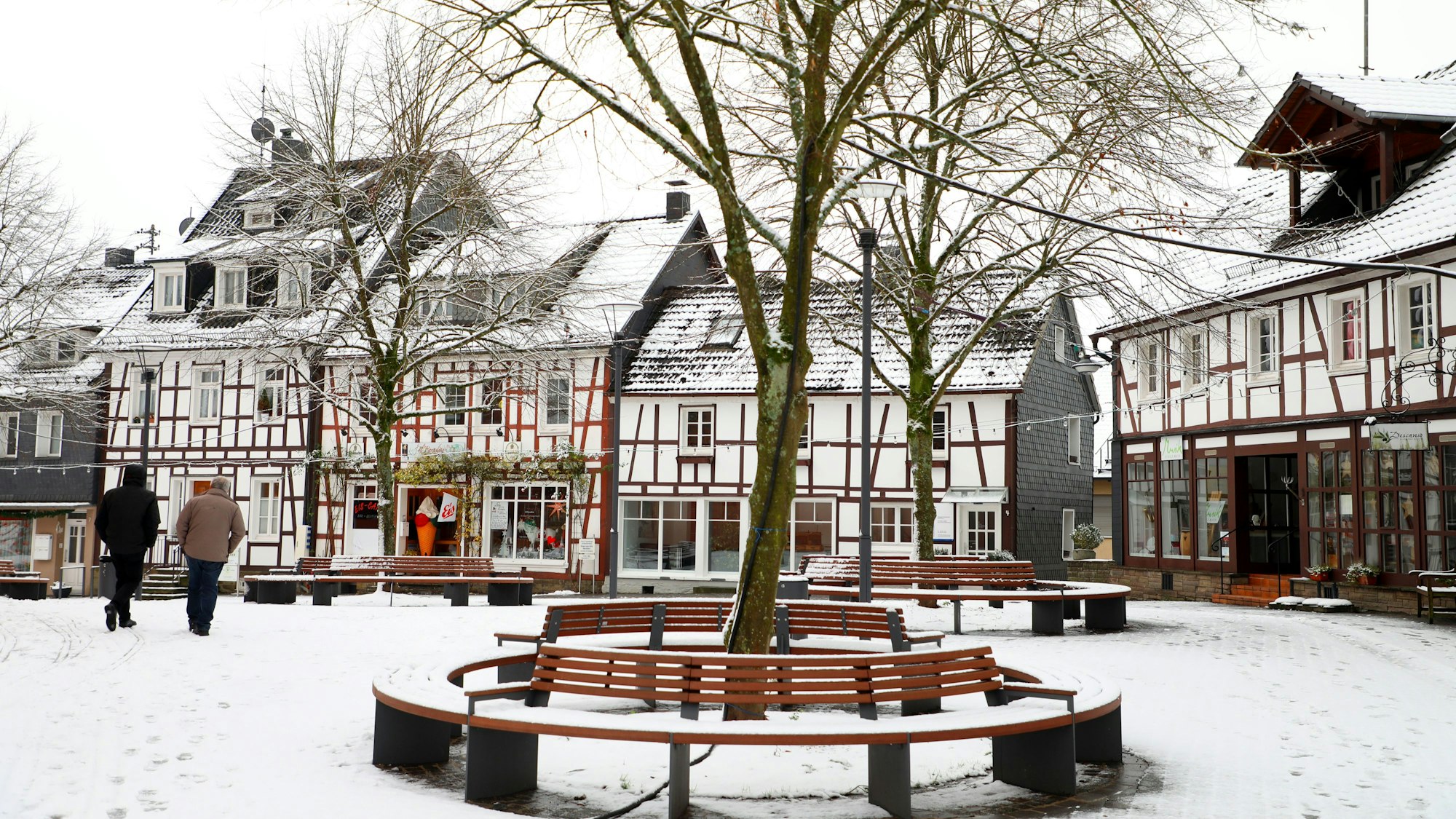 Fachwerkhäuser säumen einen Platz mit Bäumen.