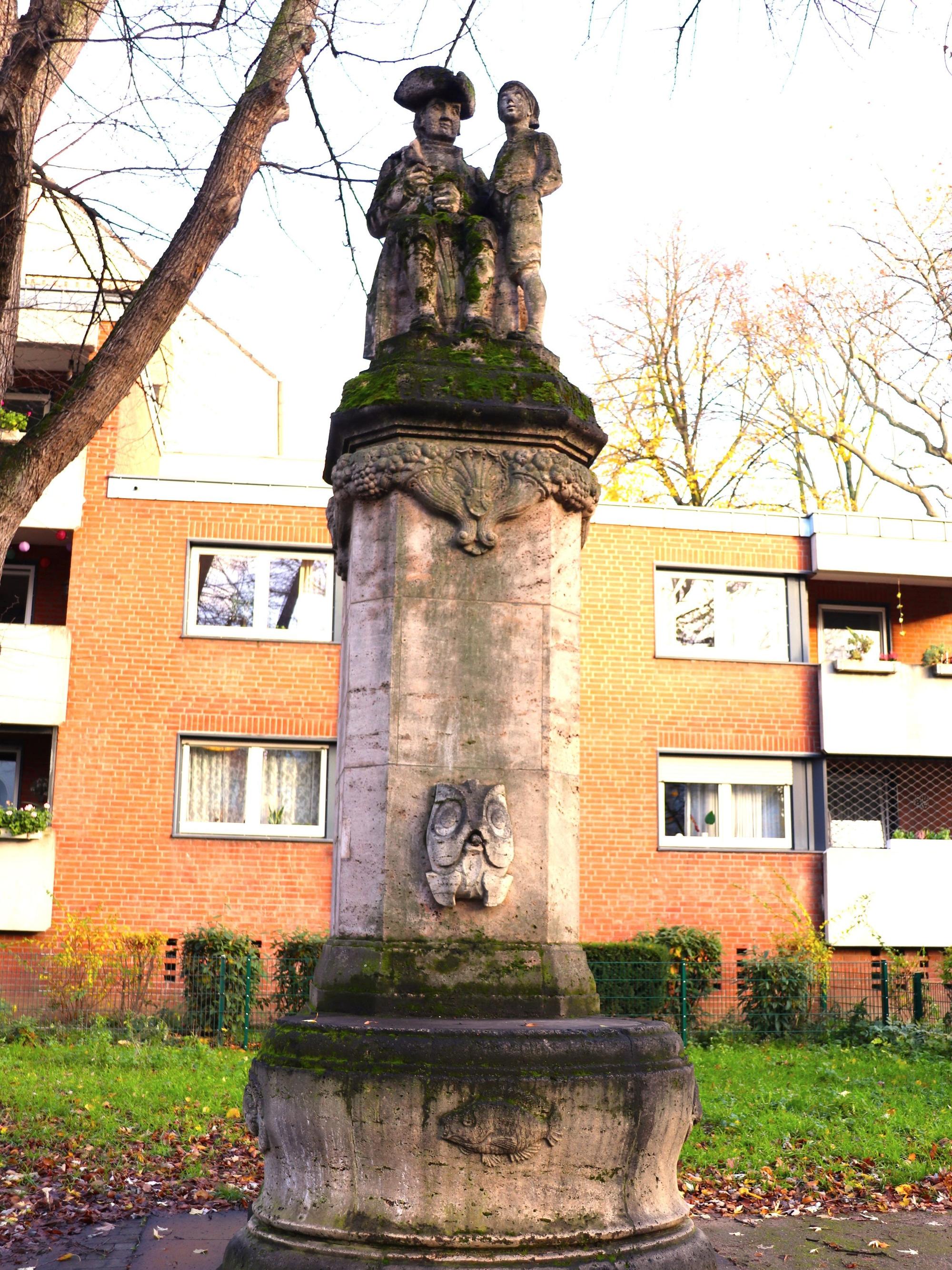 Der Hänneschen-Brunnen mit Pfeiler und Wasserbecken.