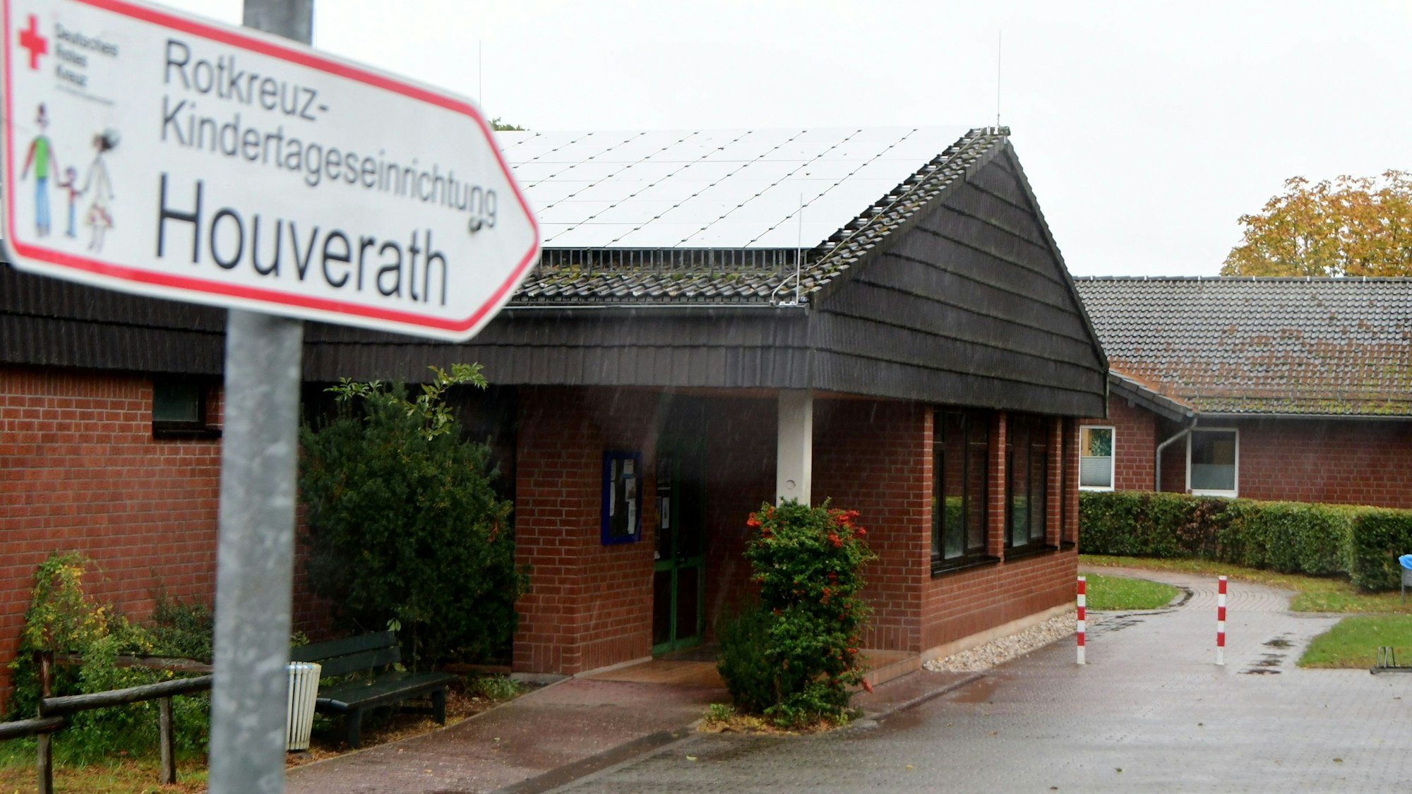 Da Foto zeigt die Kindertagesstätte Houverath. Im Vordergrund ein Wegweiser..