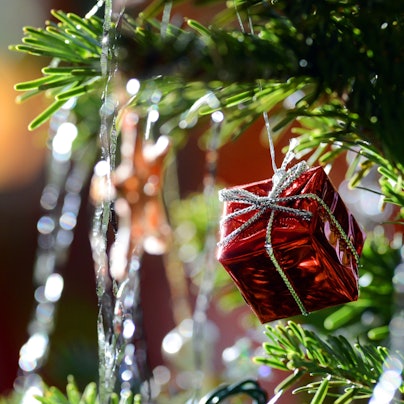 Ein kleines rotes Geschenkpaket als Weihnachtsbaumanhänger und Lametta hängen am 30.12.2012 an einem Weihnachtsbaum.