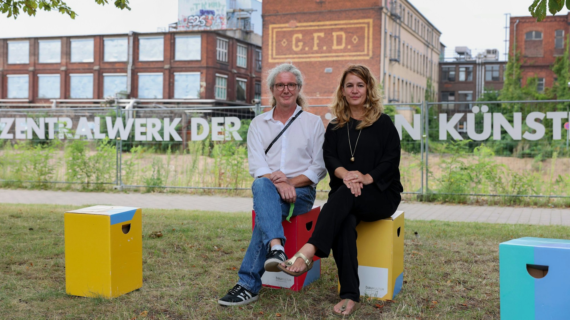 Zwei Frauen sitzen auf Kisten vor dem Otto-und-Langen-Quartier.