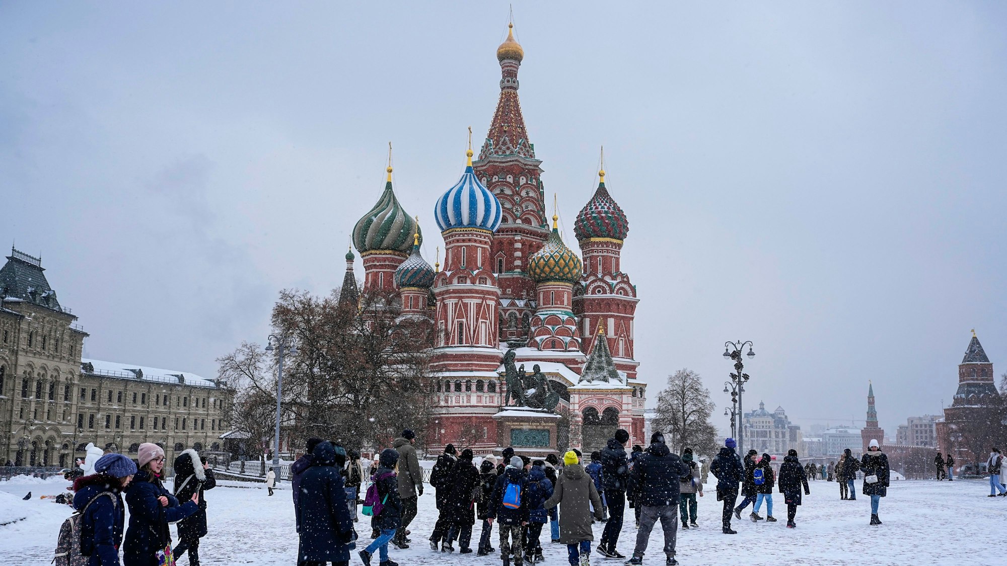 28.11.2023, Russland, Moskau: Menschen gehen über den schneebedeckten Roten Platz, während die Basilius-Kathedrale im Hintergund zu sehen ist. Foto: Alexander Zemlianichenko/AP/dpa +++ dpa-Bildfunk +++