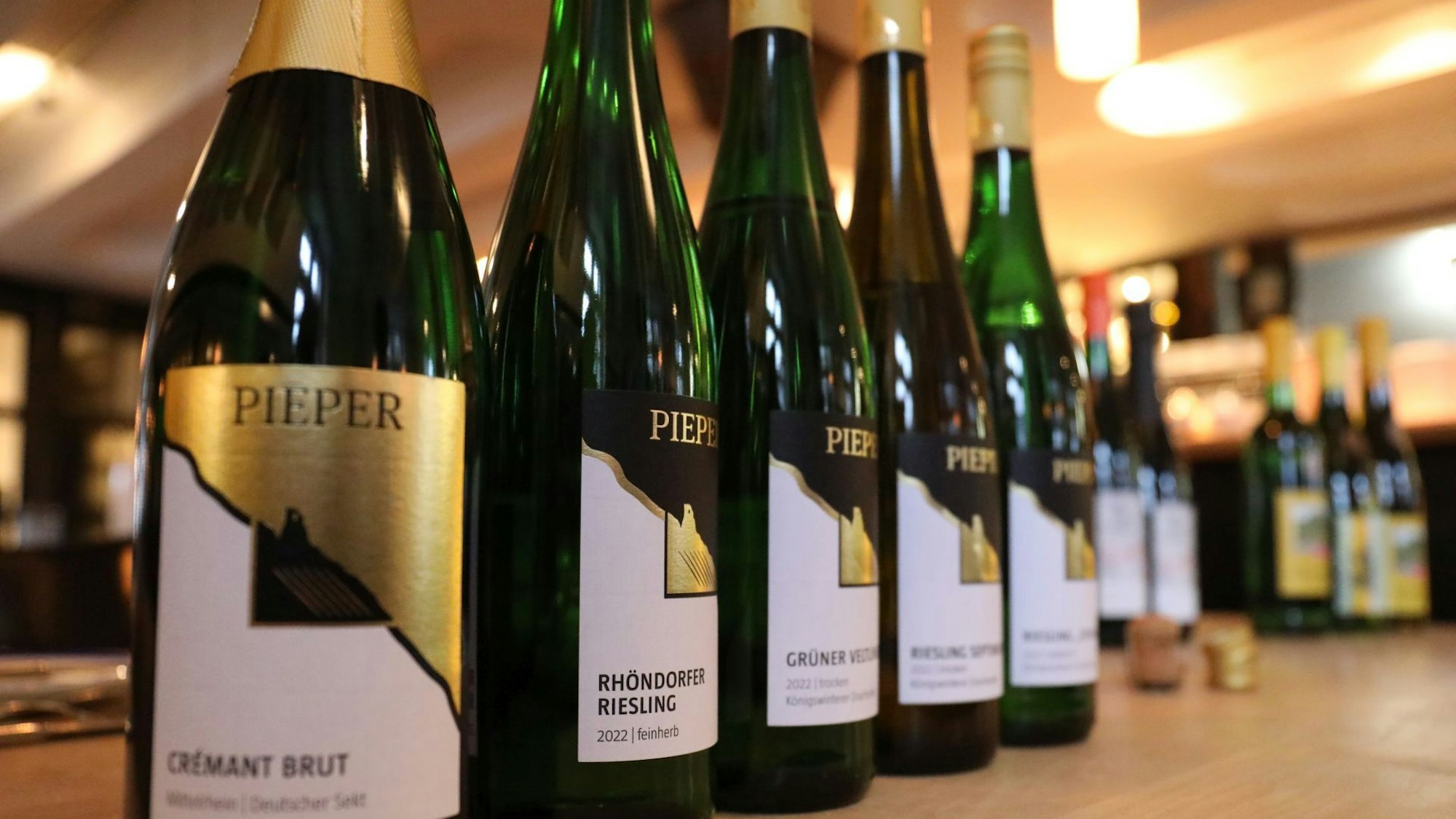 Zuerst kommen die weißen Trauben in die Gläser. Flaschen vom Weingut Pieper stehen aufgereiht auf einem Tisch zum Testen.
