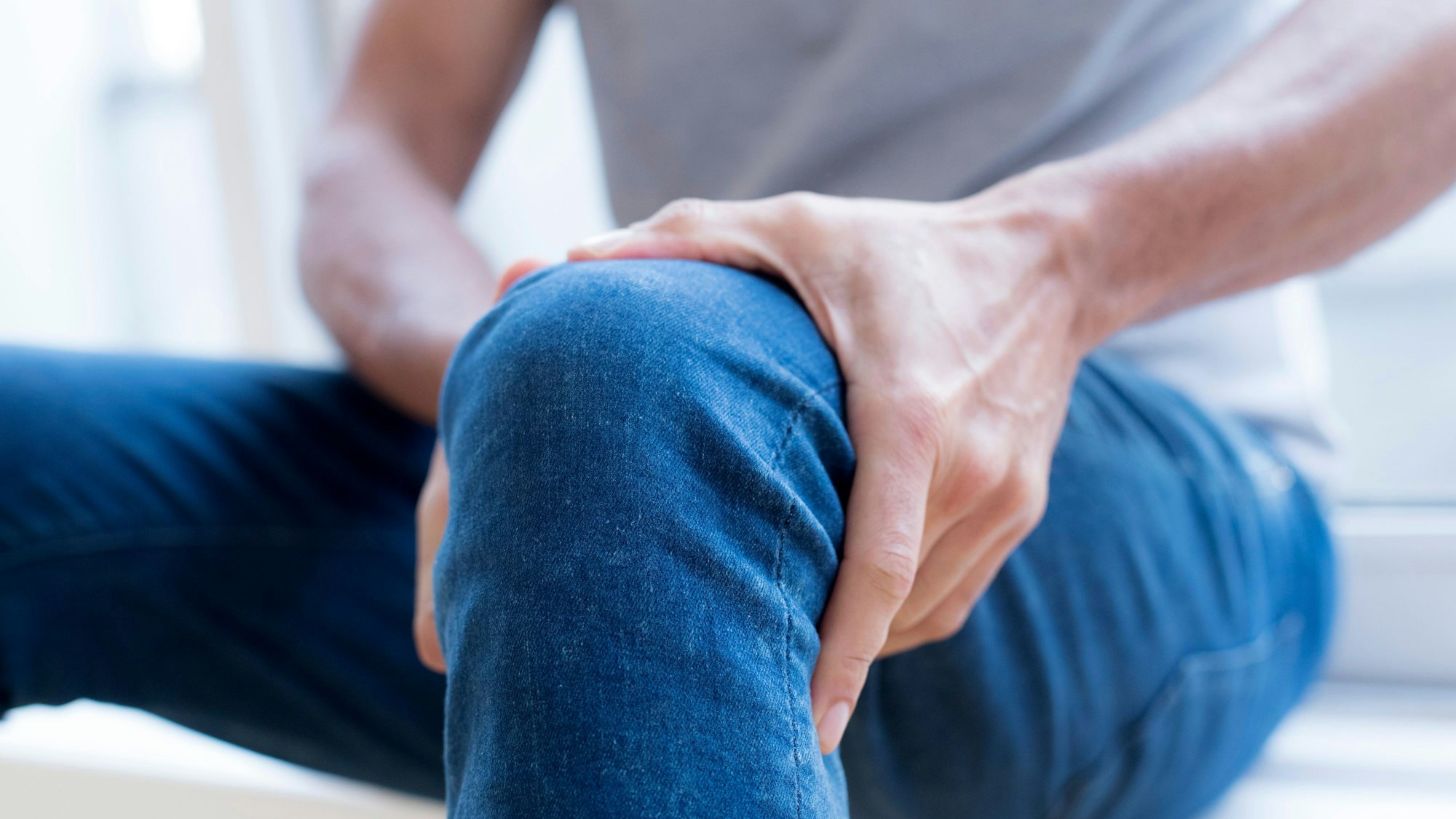 Ein Mann hält sein Bein fest.