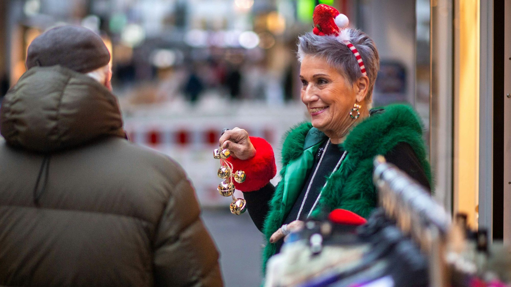 Das Bild zeigt die Filialleiterin von Donna 2000, die mit einem Glöckchen in der Hand Passanten die Aktion erklärt.