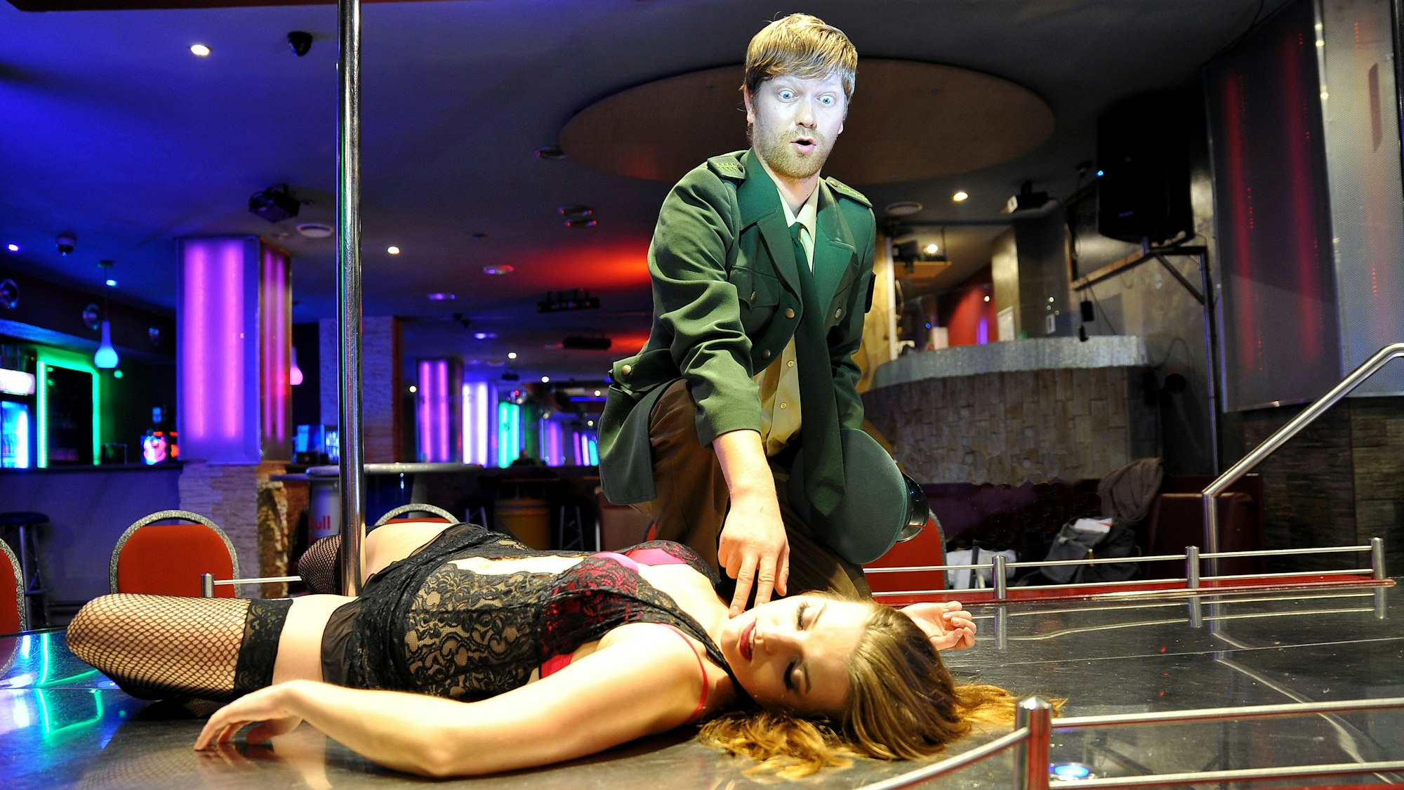 Szene aus dem Stück: Ein Polizist prüft den Puls einer Tänzerin, die auf dem Boden liegt.
