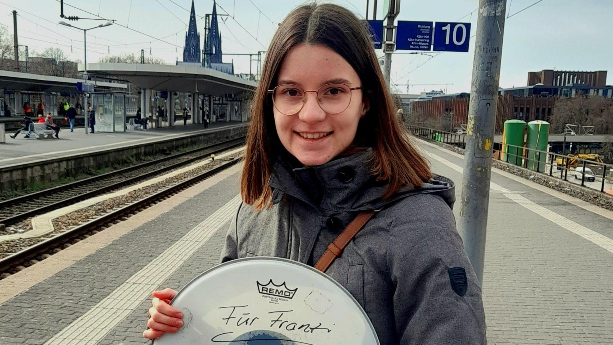 Die Teenagerin Franziska steht mit einer Trophäe ihrer Kölner Lieblingsband am Bahngleis des Deutzer Bahnhofs.