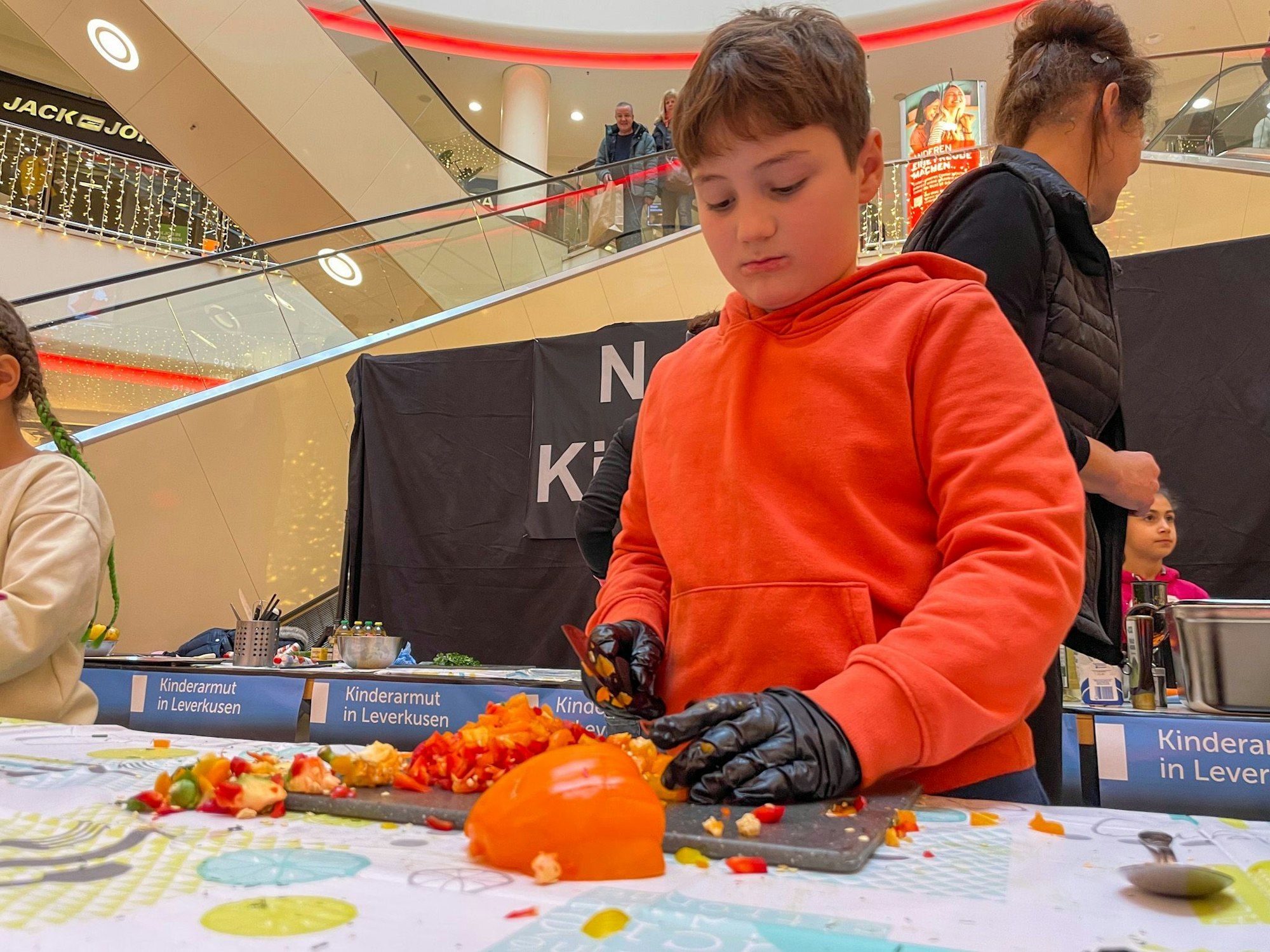 Ein Junge schneidet rote und orange Paprika.