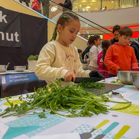 Ein Mädchen schneidet Grünzeug.
