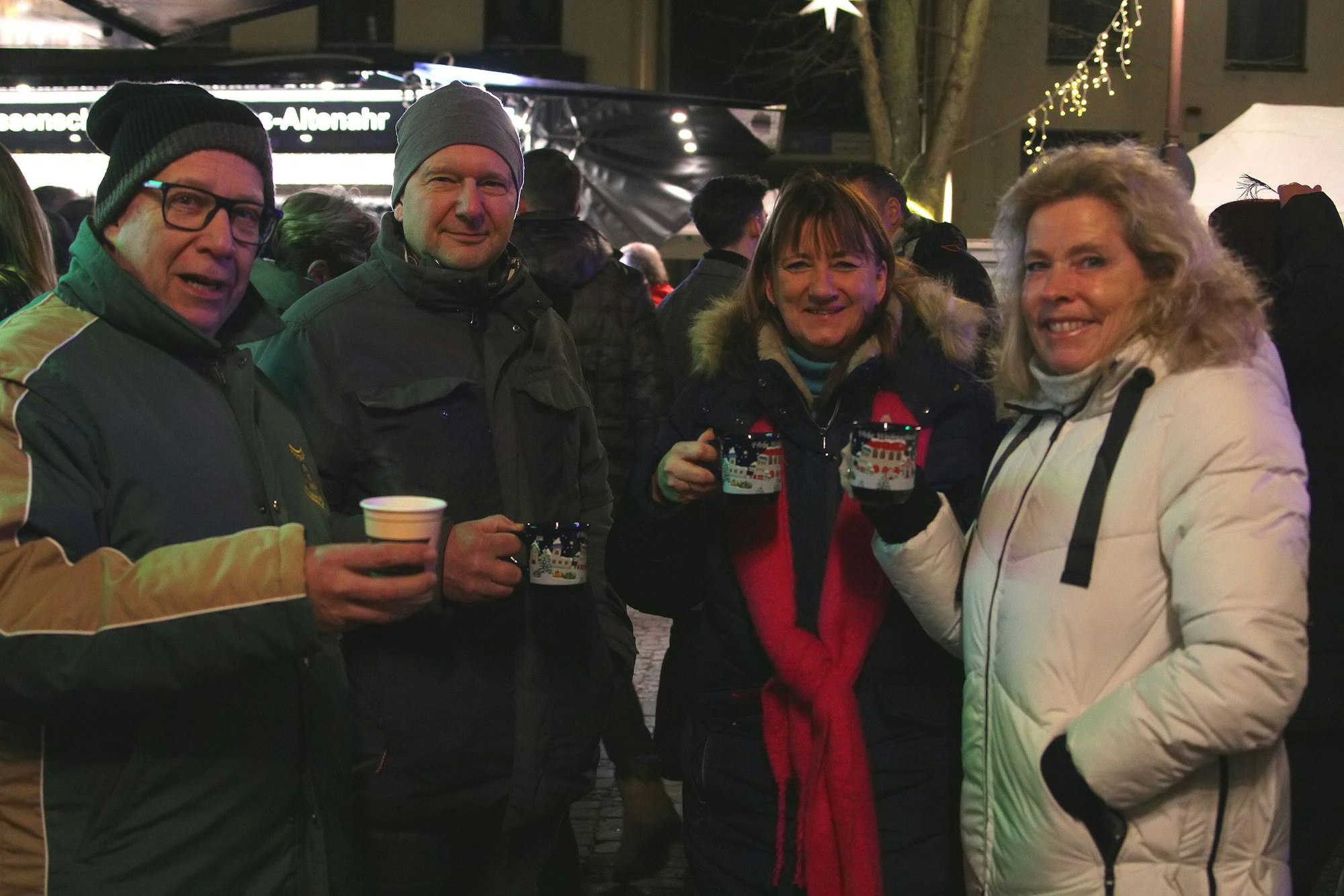 Vier Leute stoßen mit Glühweinbechern an.