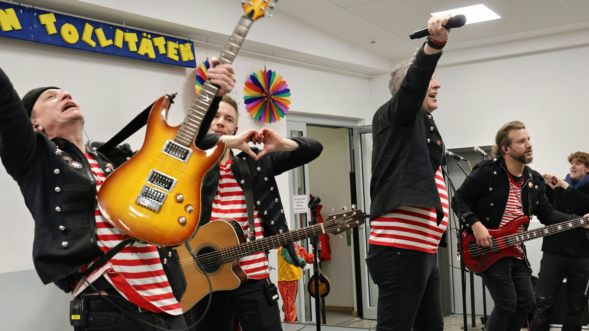 Ausgelassen performen die Kölner Musiker in roten Ringelshirts und schwarzen Bandkostümen auf der Bühne.