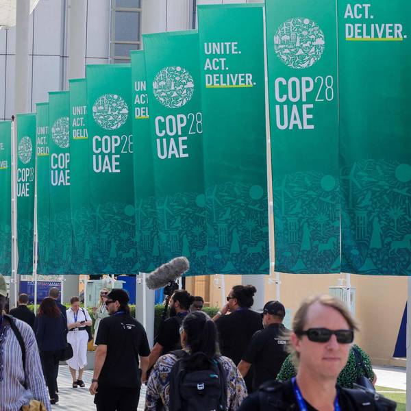Participants walk past banners at the COP28 United Nations climate summit in Dubai on December 3, 2023. (Photo by Giuseppe CACACE / AFP)