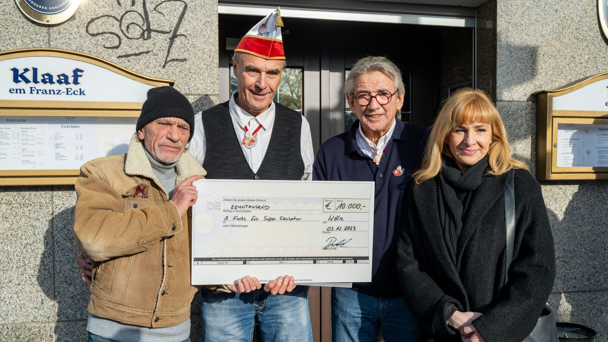 Anton Fuchs (v.l.n.r.), Rüdiger Brühl, Bernd Stumm (Kassenwart) und Heike Haupt stehen vor dem Klaaf im Franz-Eck. Fuchs und Brühl halten einen großen Scheck.