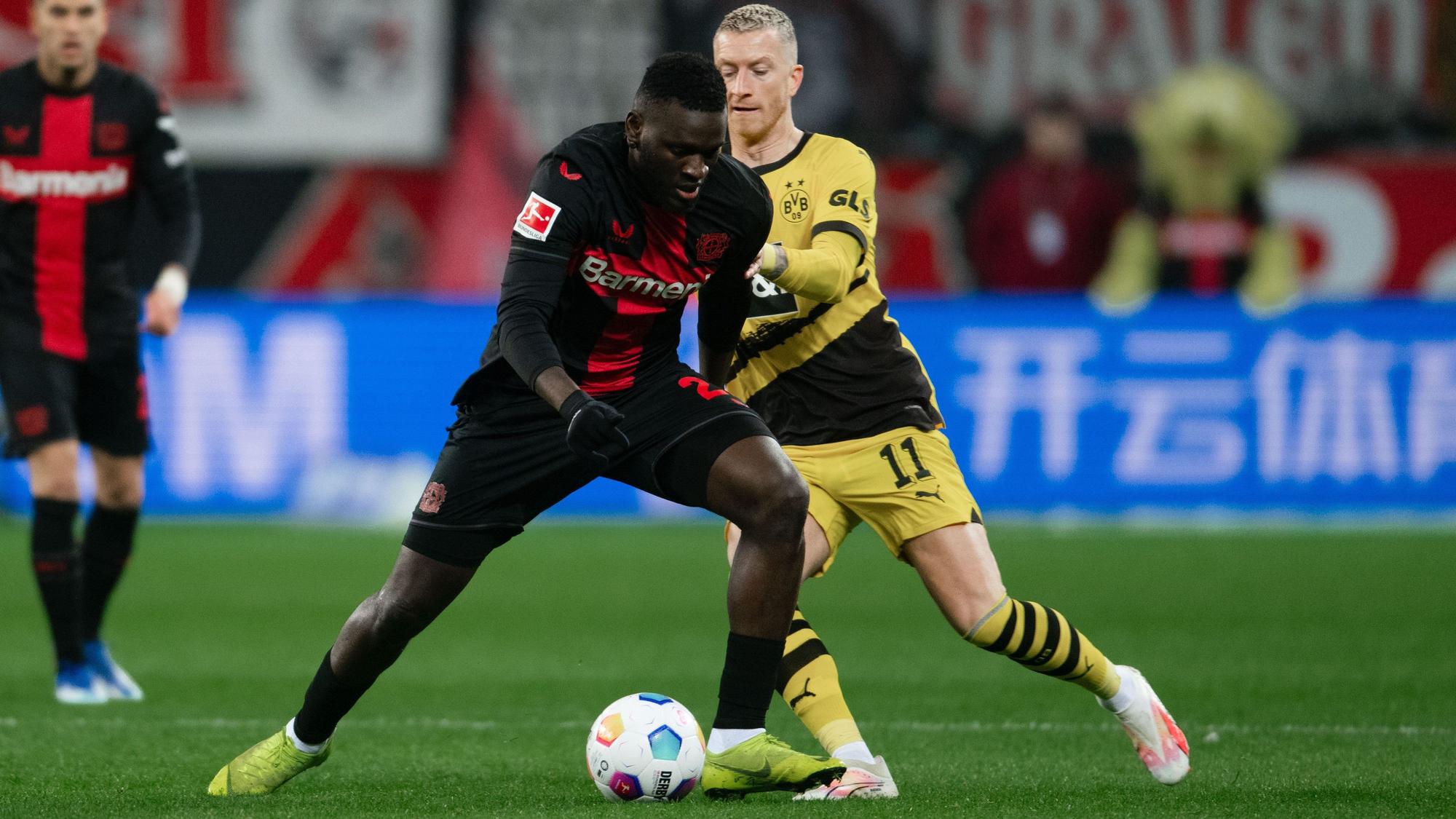 Leverkusens Victor Boniface (l) und Dortmunds Marco Reus kämpfen um den Ball.