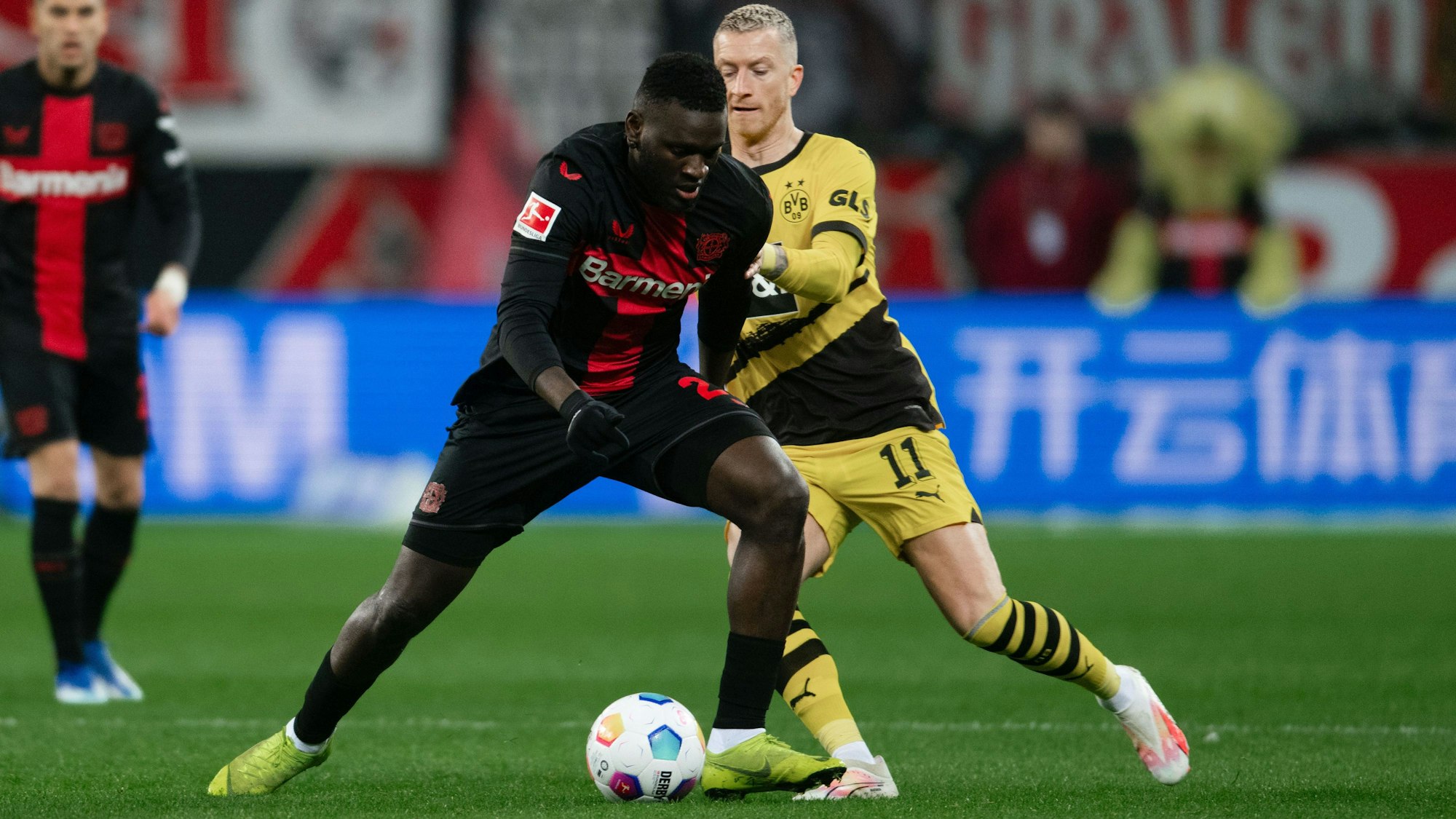 Leverkusens Victor Boniface (l) und Dortmunds Marco Reus kämpfen um den Ball.