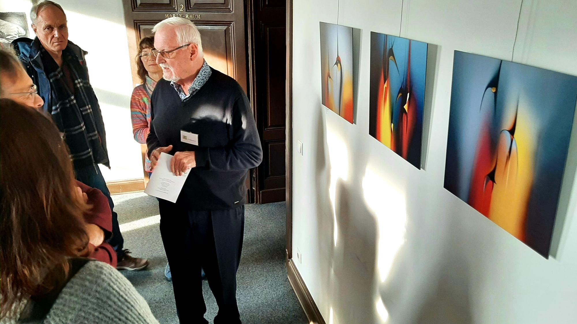 Jahresausstellung Leichlinger Künstlerinnen und Künstler 2023 im Bürgerhaus Am Hammer in Leichlingen. Wolfgang Ahrens erklärt sein Bilder einigen Besucherinnen und Besuchern.