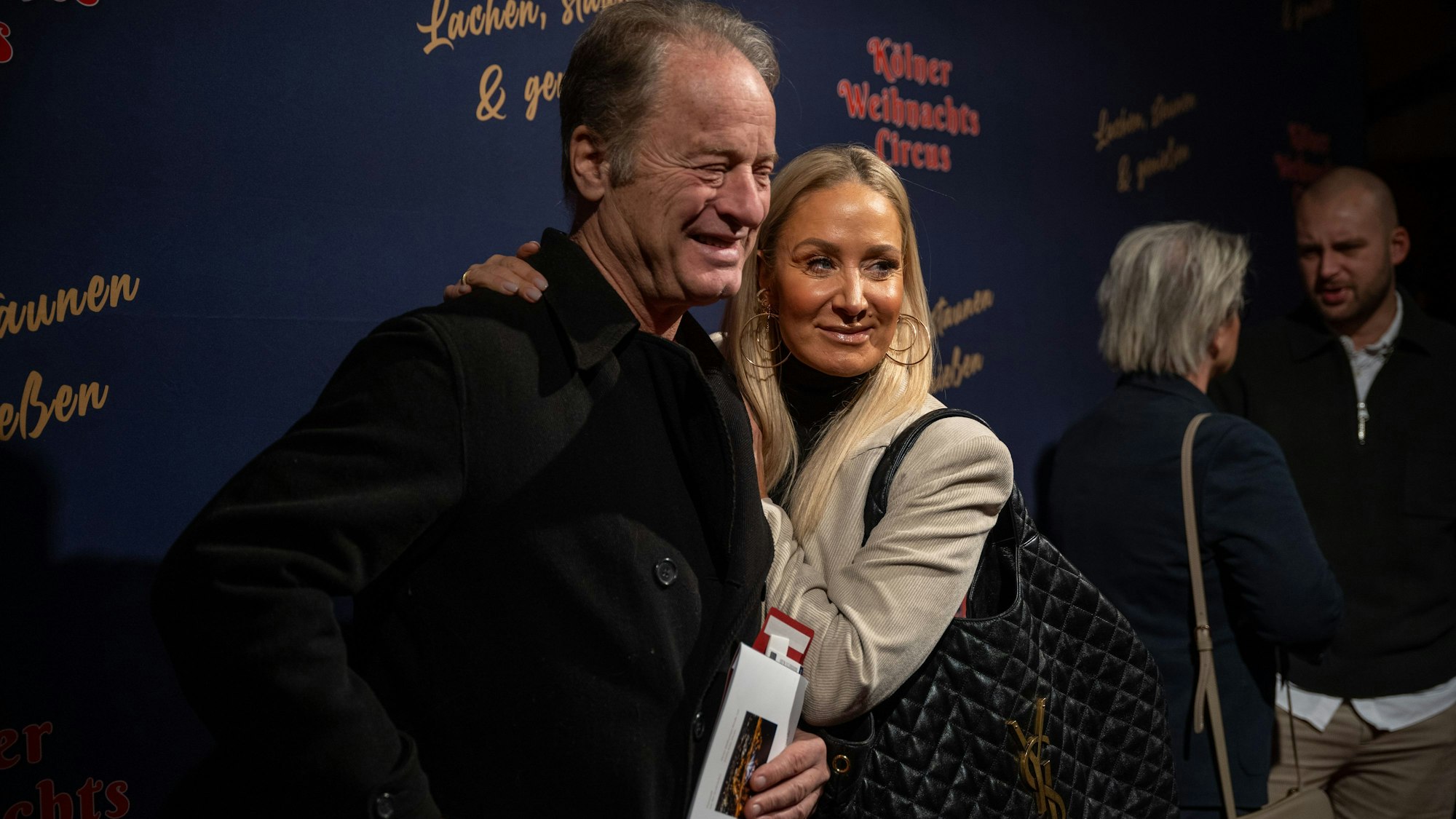 Tom Gerhardt und Janine Kunze lächeln vor dem Kölner Weihnachtscircus in die Kamera.
