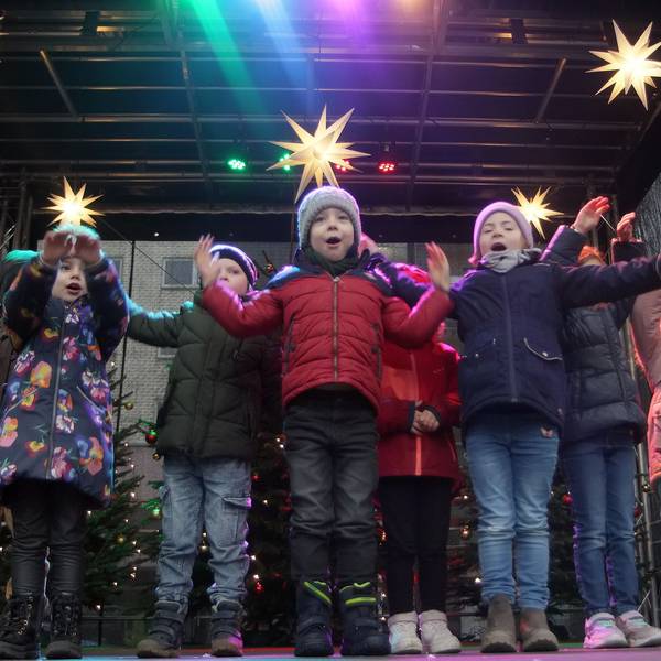 Kinder stehen auf einer weihnachtlich geschmückten Bühne.