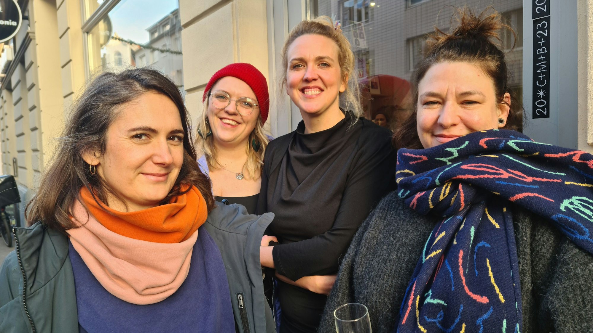 Vier Frauen stehen lachend vor einer Ladenfront.