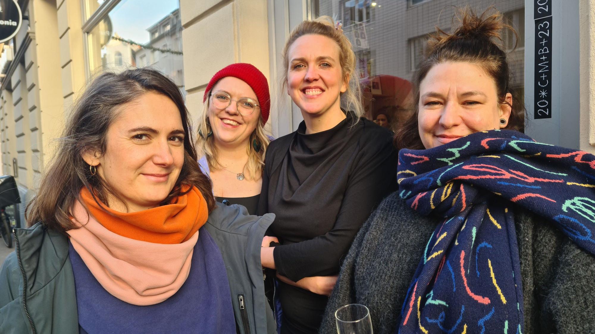 Vier Frauen stehen lachend vor einer Ladenfront.