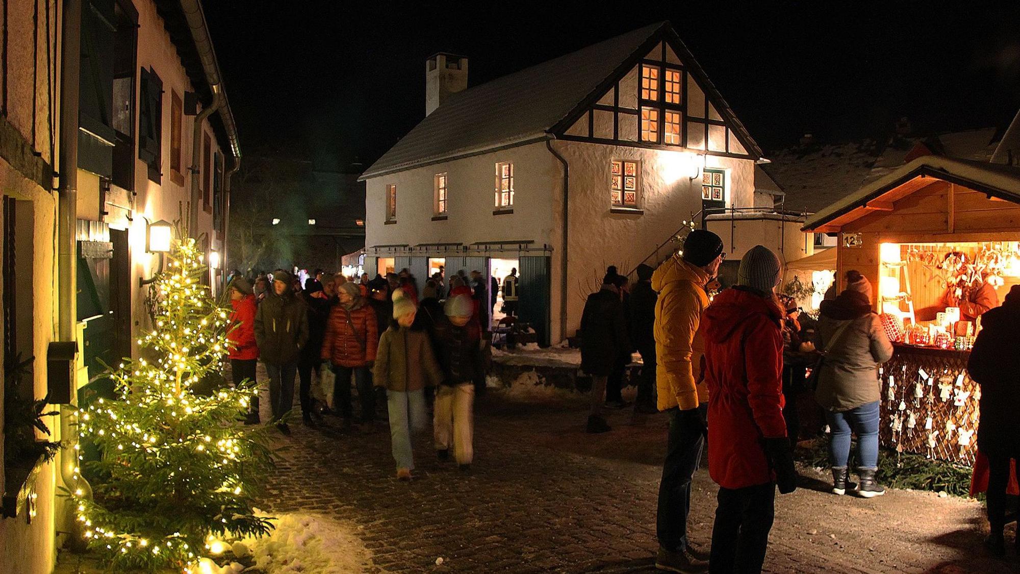 Der Burgbering in Kronenburg ist weihnachtlich geschmückt, zahlreiche Menschen schlendern an Buden und Häusern vorbei