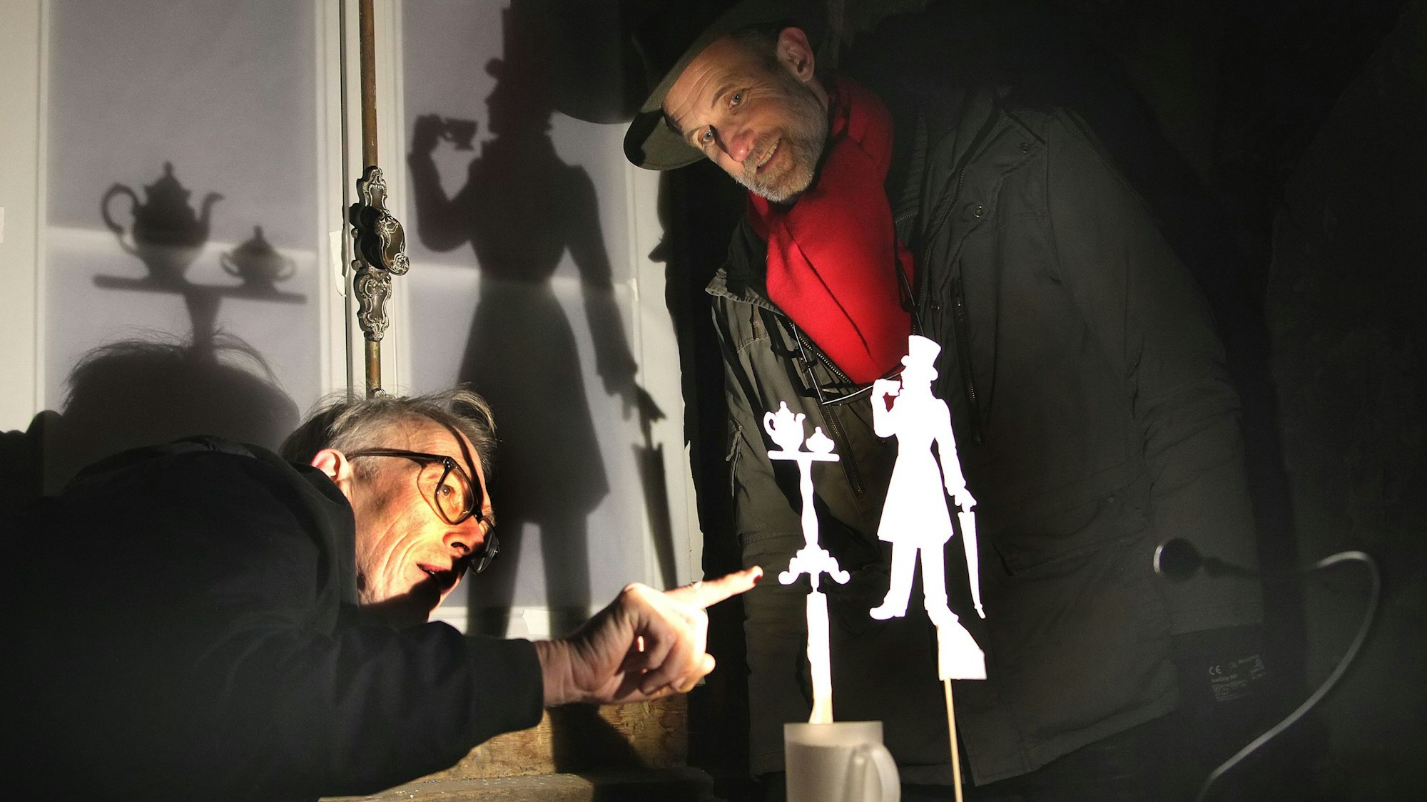 Zwei Männer begutachten eine kleine, aus Papier ausgeschnittene Figur