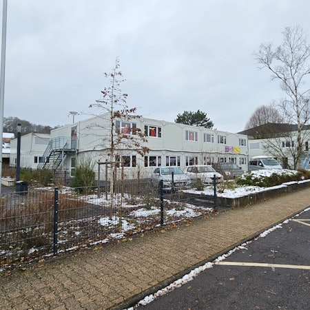 Blick auf die Container an der Kaller Grundschule und der Sporthalle im Hintergrund.