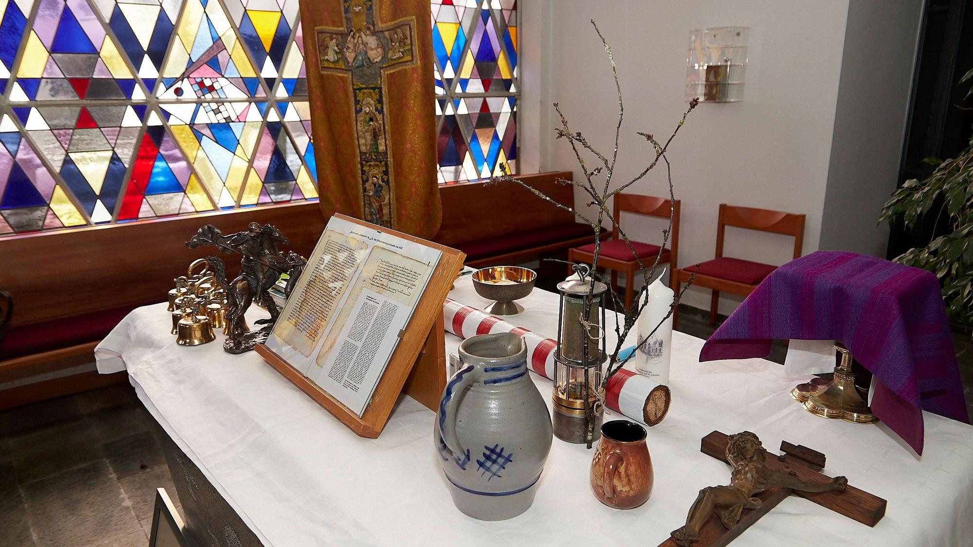 Ein Messgewand, ein Kreuz, eine Berglampe und zahlreiche weitere Gegenstände liegen auf einem Tisch: Es sind Geschenke aus den 17 Gemeinden für den neuen Pfarrer der GdG Schleiden-Hellenthal.