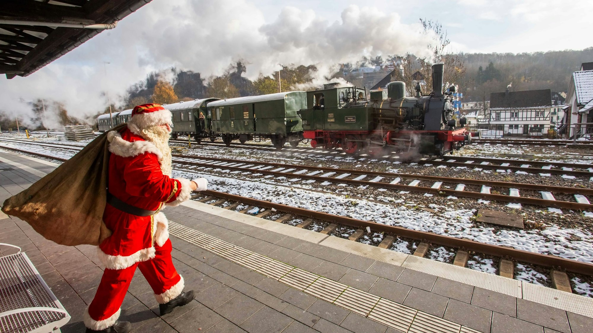 Ein Mann in Nikolaus-Kostüm steht am Bahnsteig, im Hintergrund dampft der Bergische Löwe.