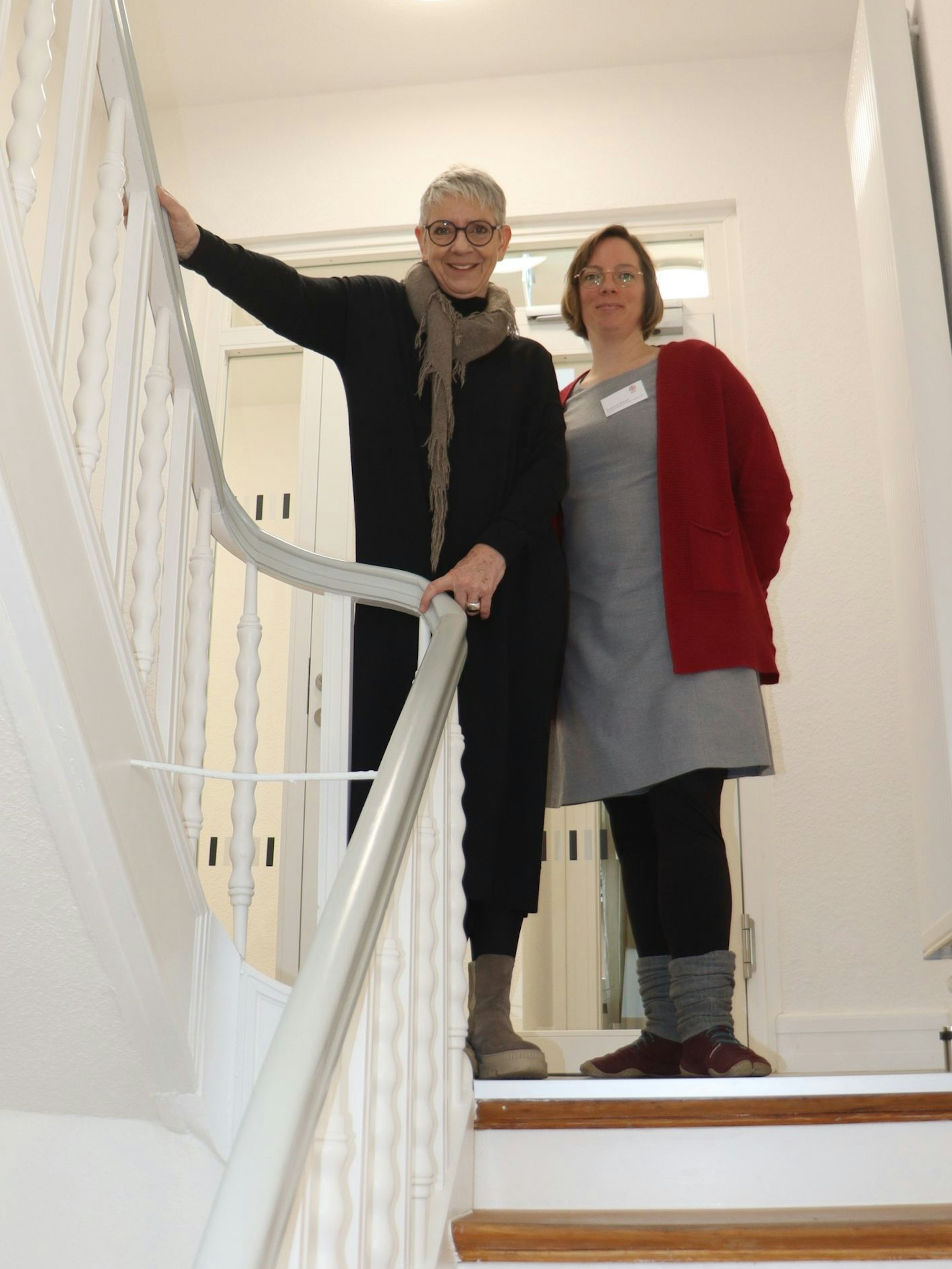 Zwei Frauen stehen im Treppenaufgang.