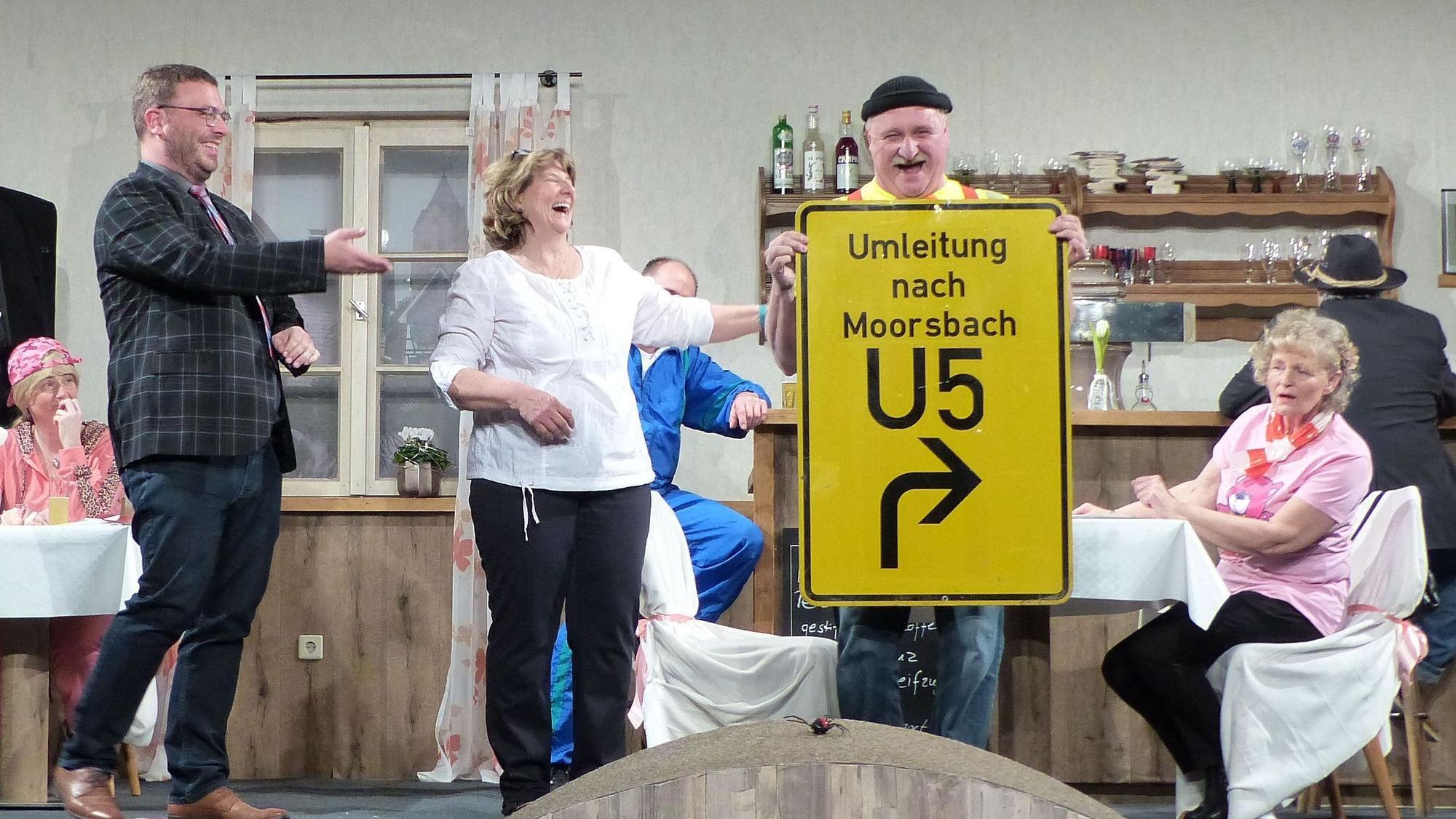 Die Darsteller auf der Bühne freuen sich über ein Verkehrsschild.