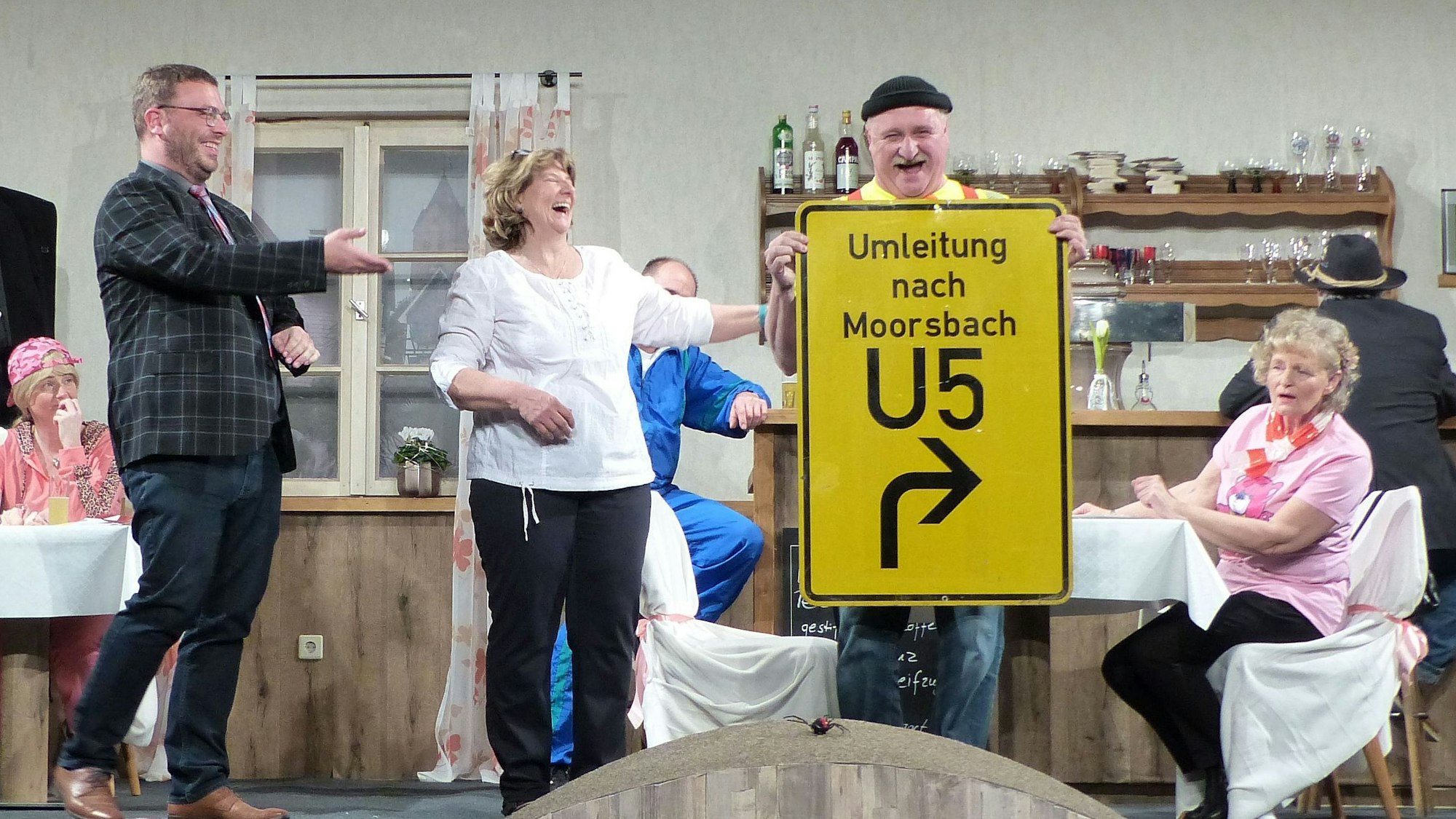 Die Darsteller auf der Bühne freuen sich über ein Verkehrsschild.