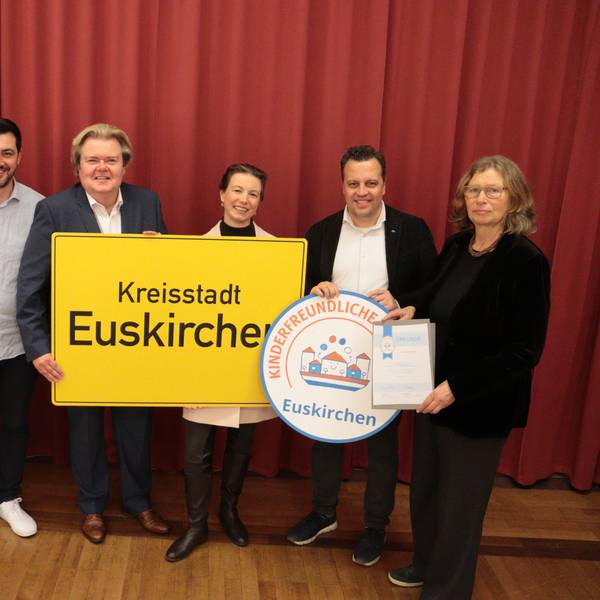 Frauen und Männer, die an der Übergabe des Siegels „Kinderfreundliche Kommune“ an die Stadt Euskirchen teilnahmen, stehen im Ratssaal nebeneinander.