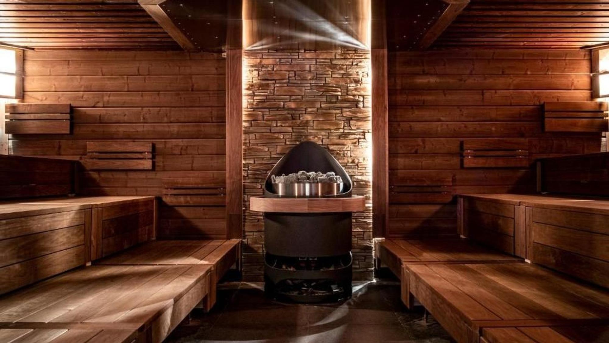 Man sieht eine Sauna von innen, mit Sauna-Ofen und Sitzbänken.