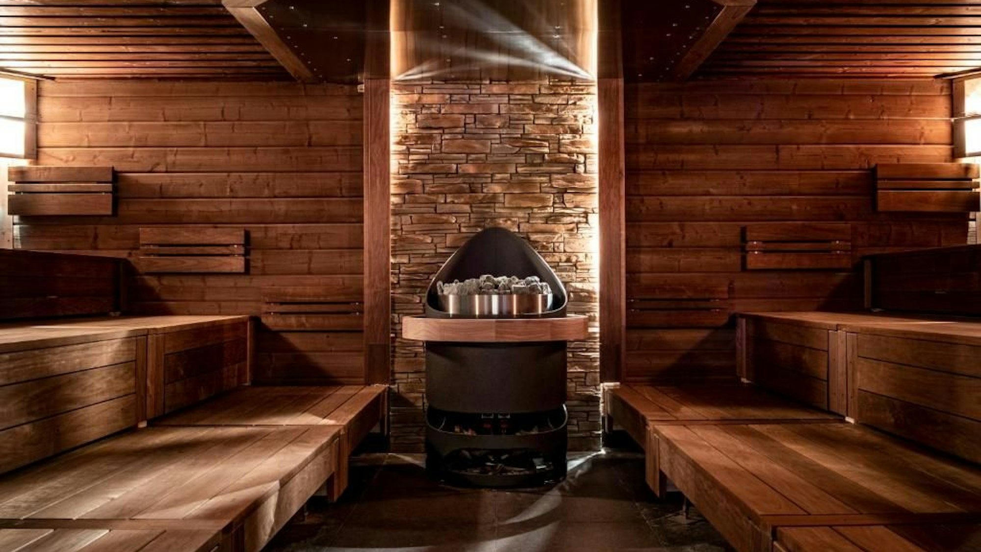 Man sieht eine Sauna von innen, mit Sauna-Ofen und Sitzbänken.