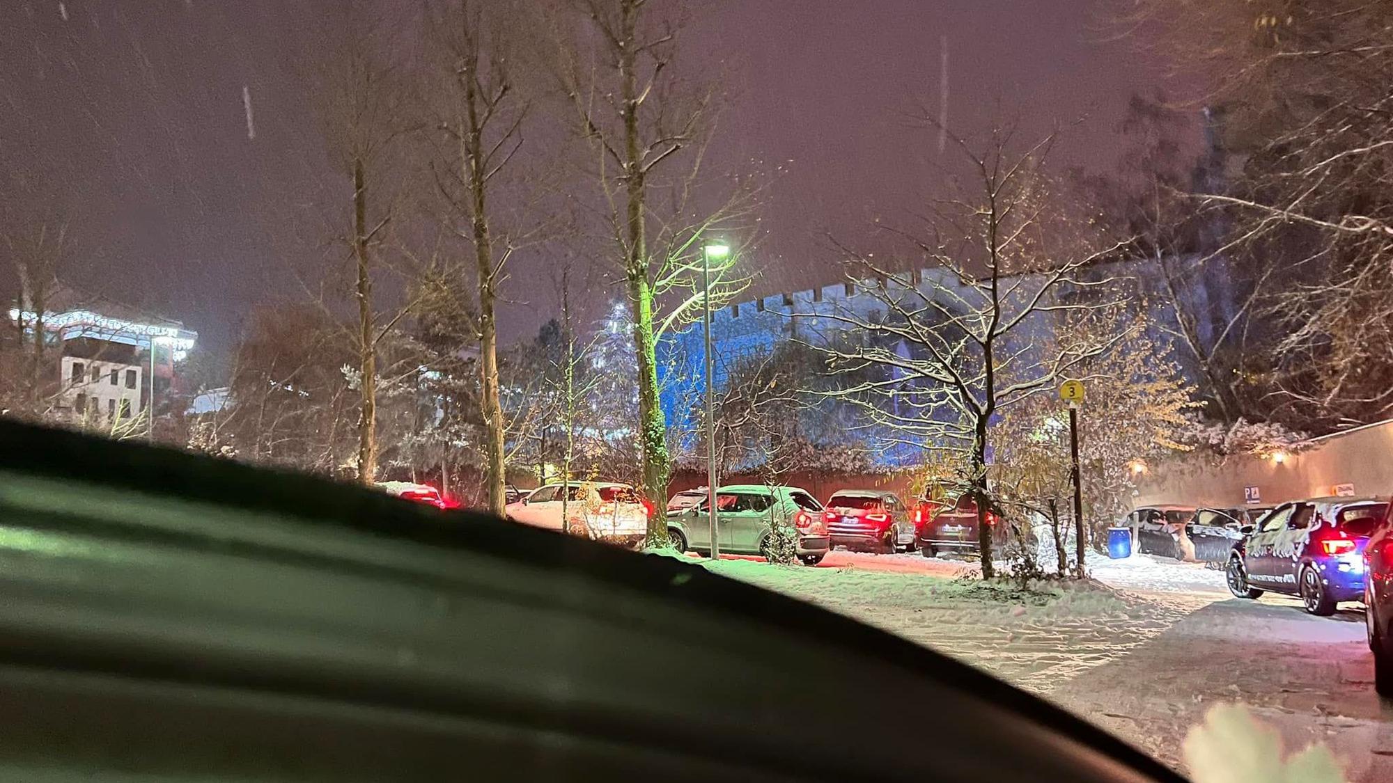 Auf dem Foto ist der tief verschneite Parkplatz des Freizeitparks Phantasialands zu sehen. Autos stehen in der Schlange mit laufenden Motoren.