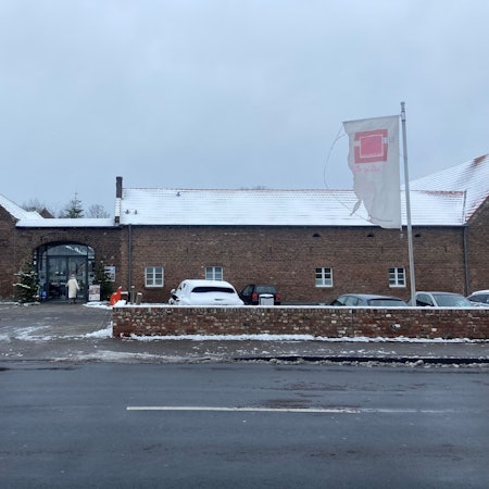 Ein großer Gutshof liegt an einer Straße, darauf ist der Schriftzug Eltzhof zu lesen.