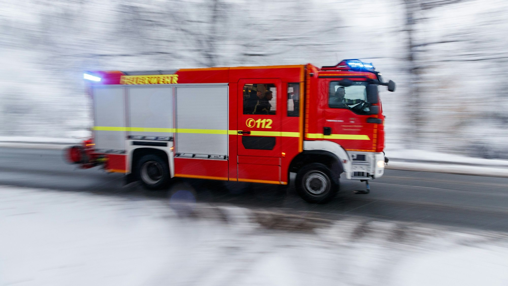 29.11.2023, Nordrhein-Westfalen, Bielefeld: Blick auf ein Fahrzeug der Feuerwehr im Einsatz mit Blaulicht. Winterlich mit Schneefall und Temperaturen um den Gefrierpunkt zeigt sich das Wetter in weiten Teilen von Nordrhein-Westfalen. Foto: Friso Gentsch/dpa +++ dpa-Bildfunk +++