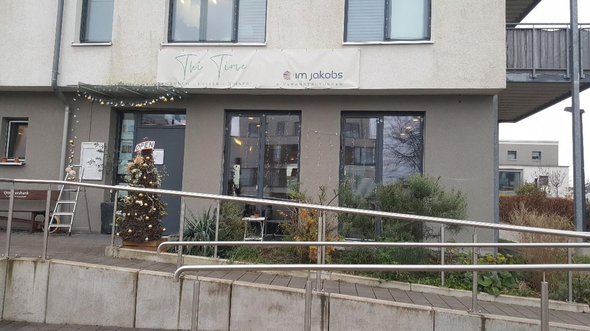 Ein mehrgeschossiges graues Gebäude beherbergt im Erdgeschoss ein Restaurant.