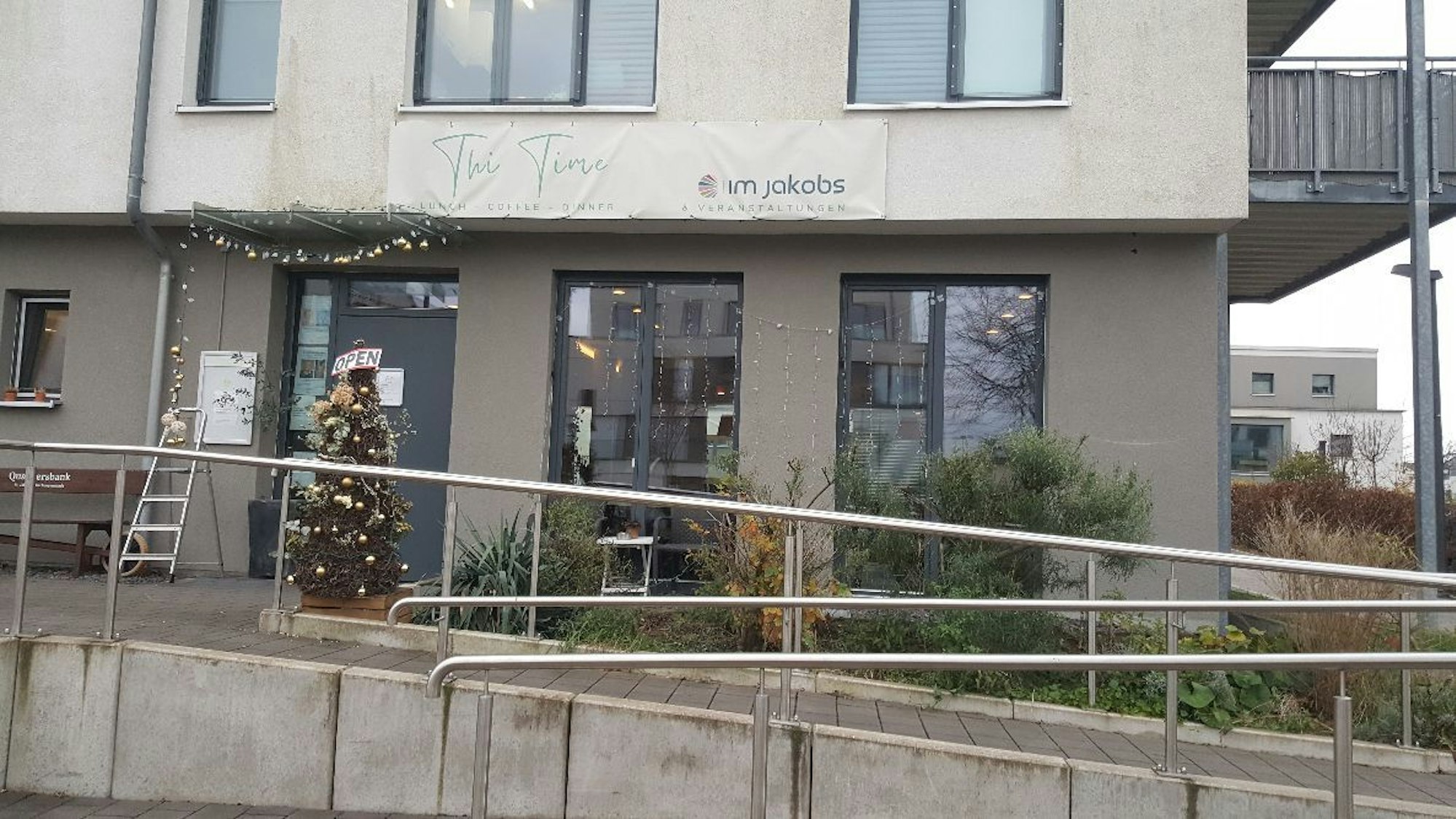 Ein mehrgeschossiges graues Gebäude beherbergt im Erdgeschoss ein Restaurant.