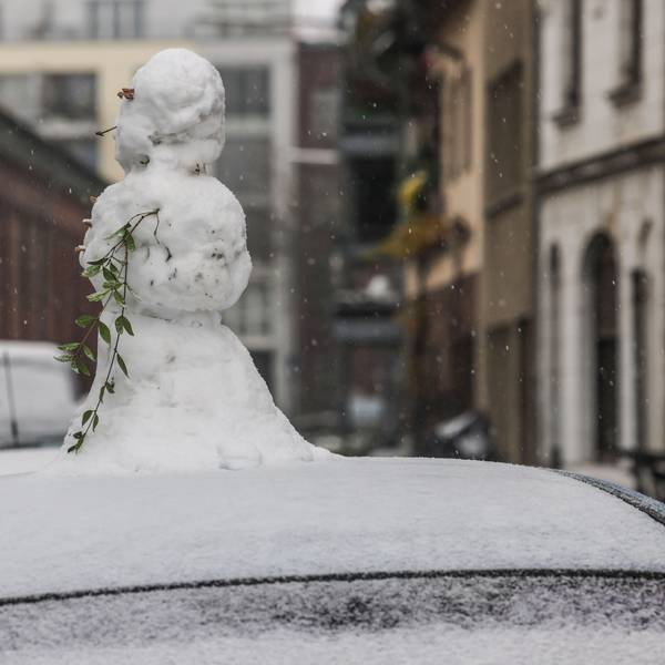 Ein Schneemann steht in Köln auf einem Autodach.