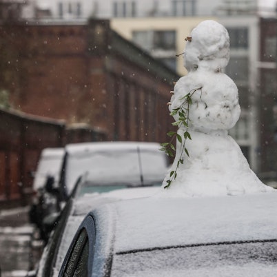 Ein Schneemann steht in Köln auf einem Autodach.