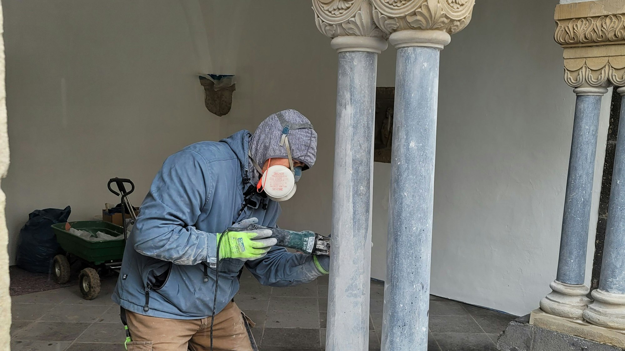 Ein Mann reinigt mit einem Spezialgerät eine Säule im Marienhof. Er trägt einen Mundschutz.