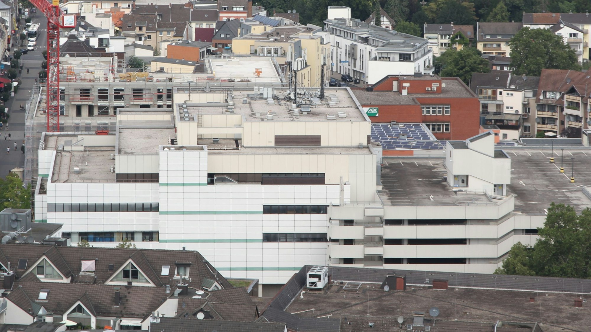Ein Kaufhaus und ein Parkhaus mit hellen Betonfassaden aus der Vogelperspektive